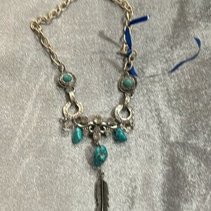 A crafted silver tone necklace with turquoise and crystal accents.